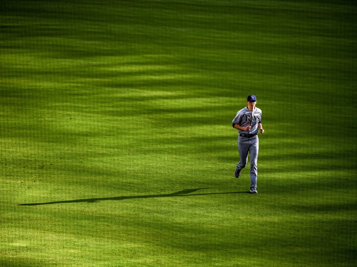 A Rays pitcher runs in the outfield